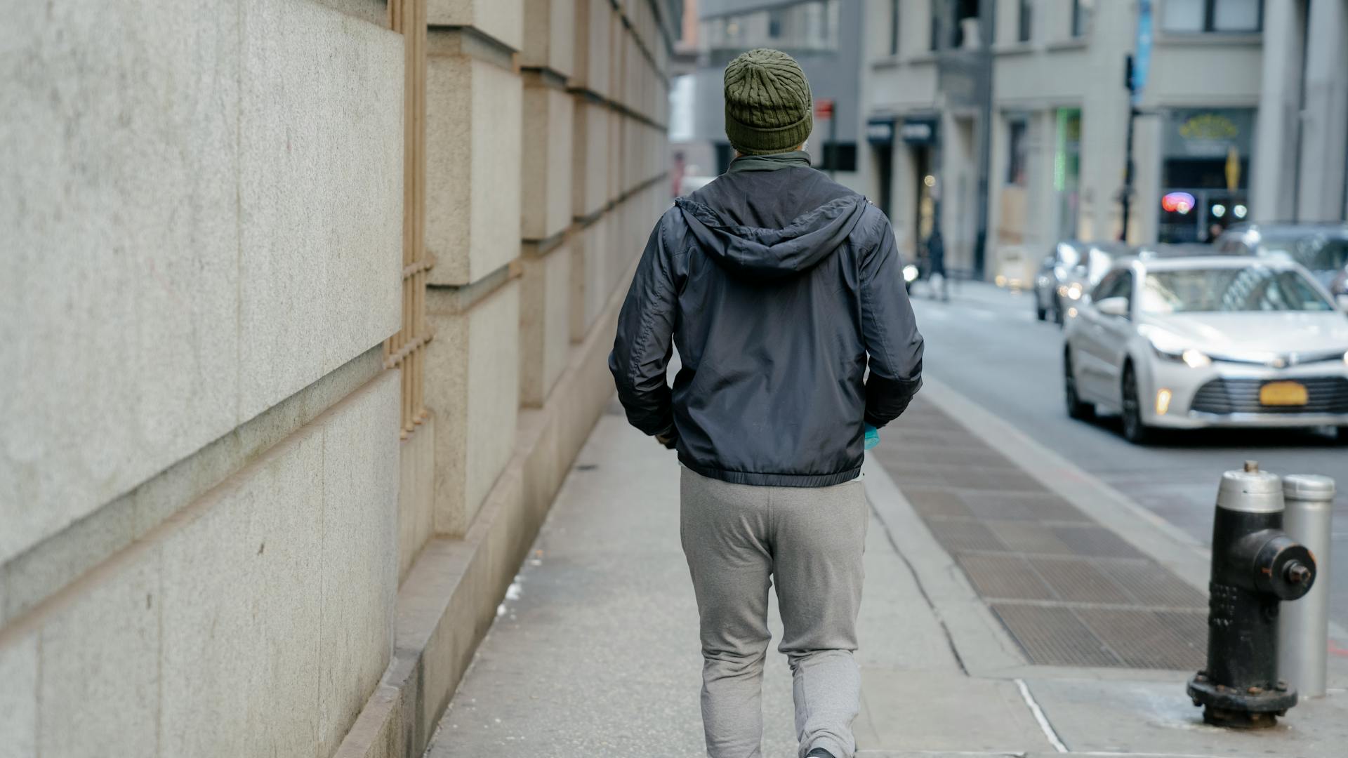 Man in a windbreaker walking a city street