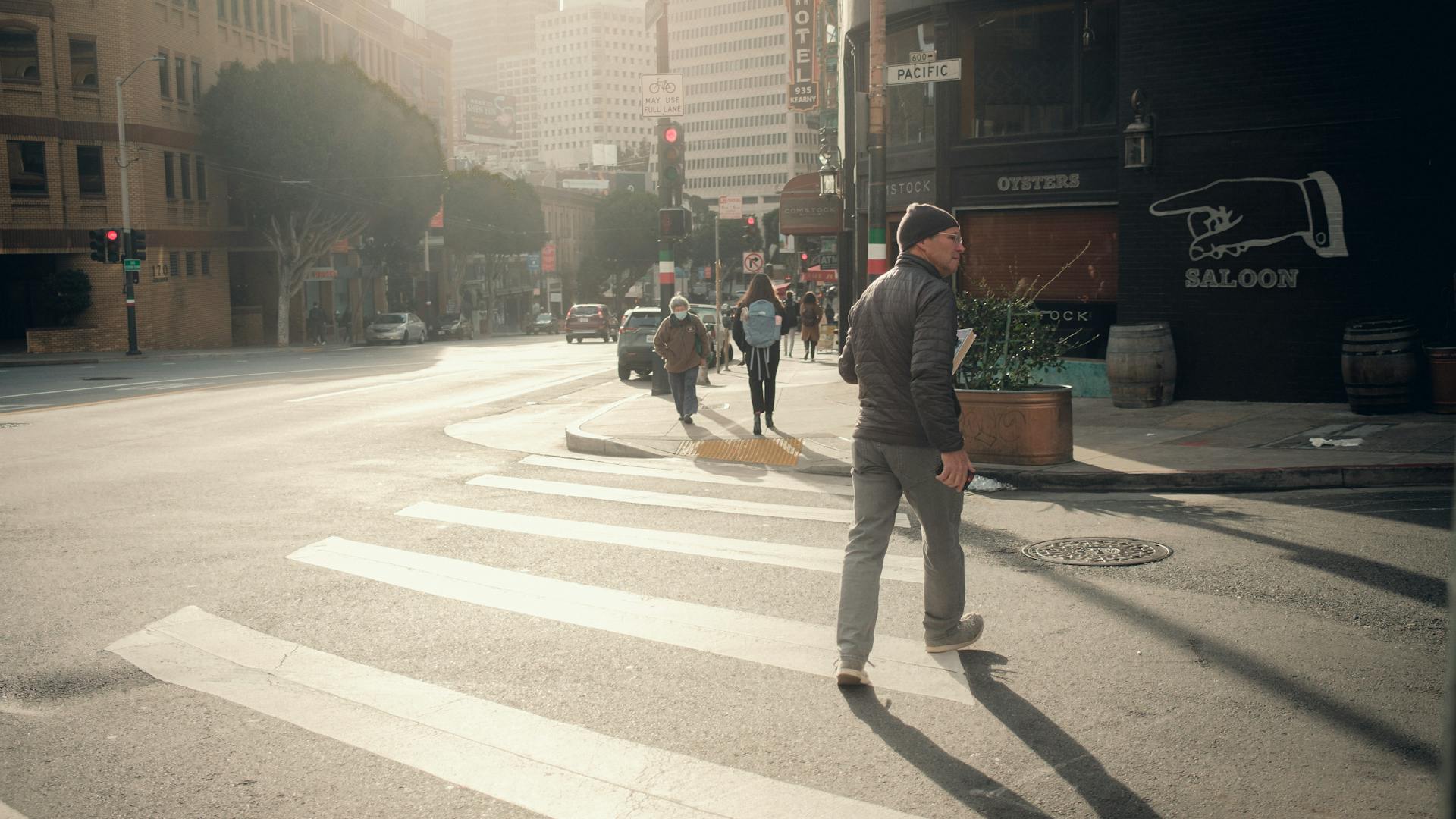 Man in a jacket crossing a downtown street